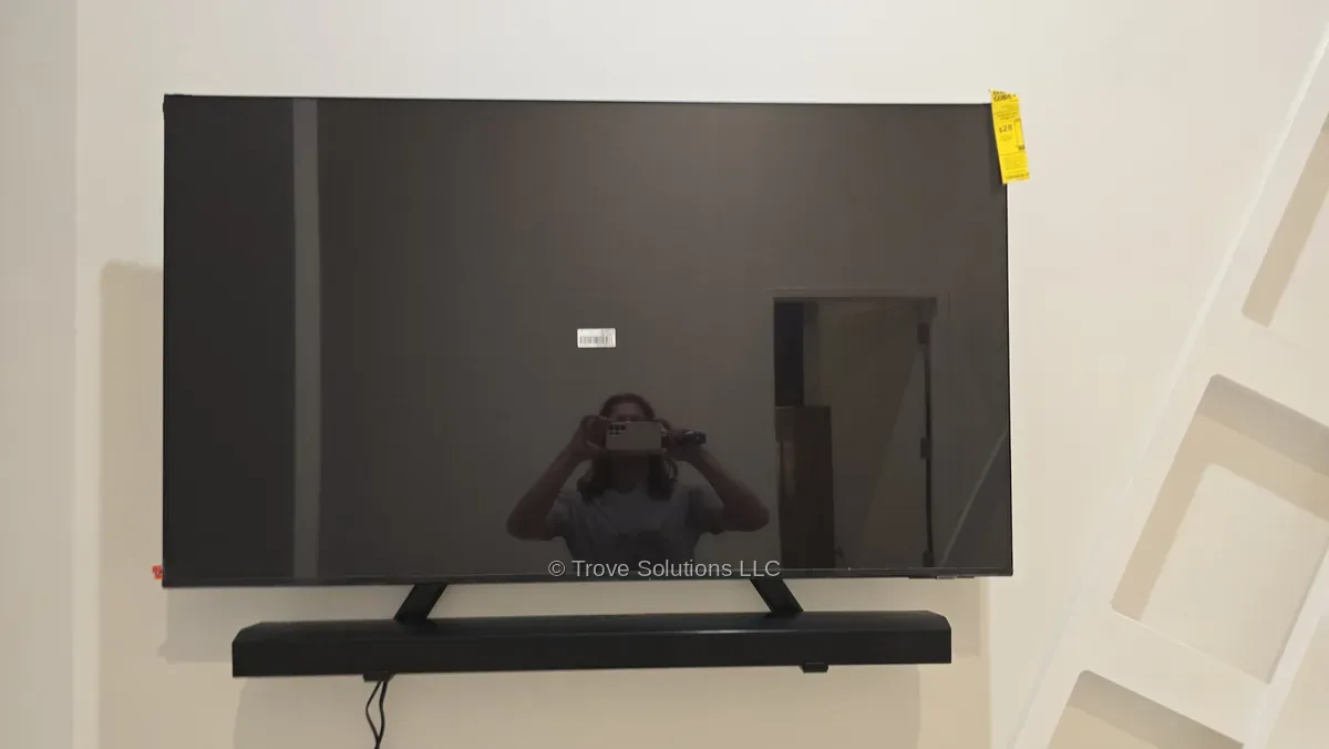 Large TV mounted on the wall above a soundbar shelf in a Manhattan apartment