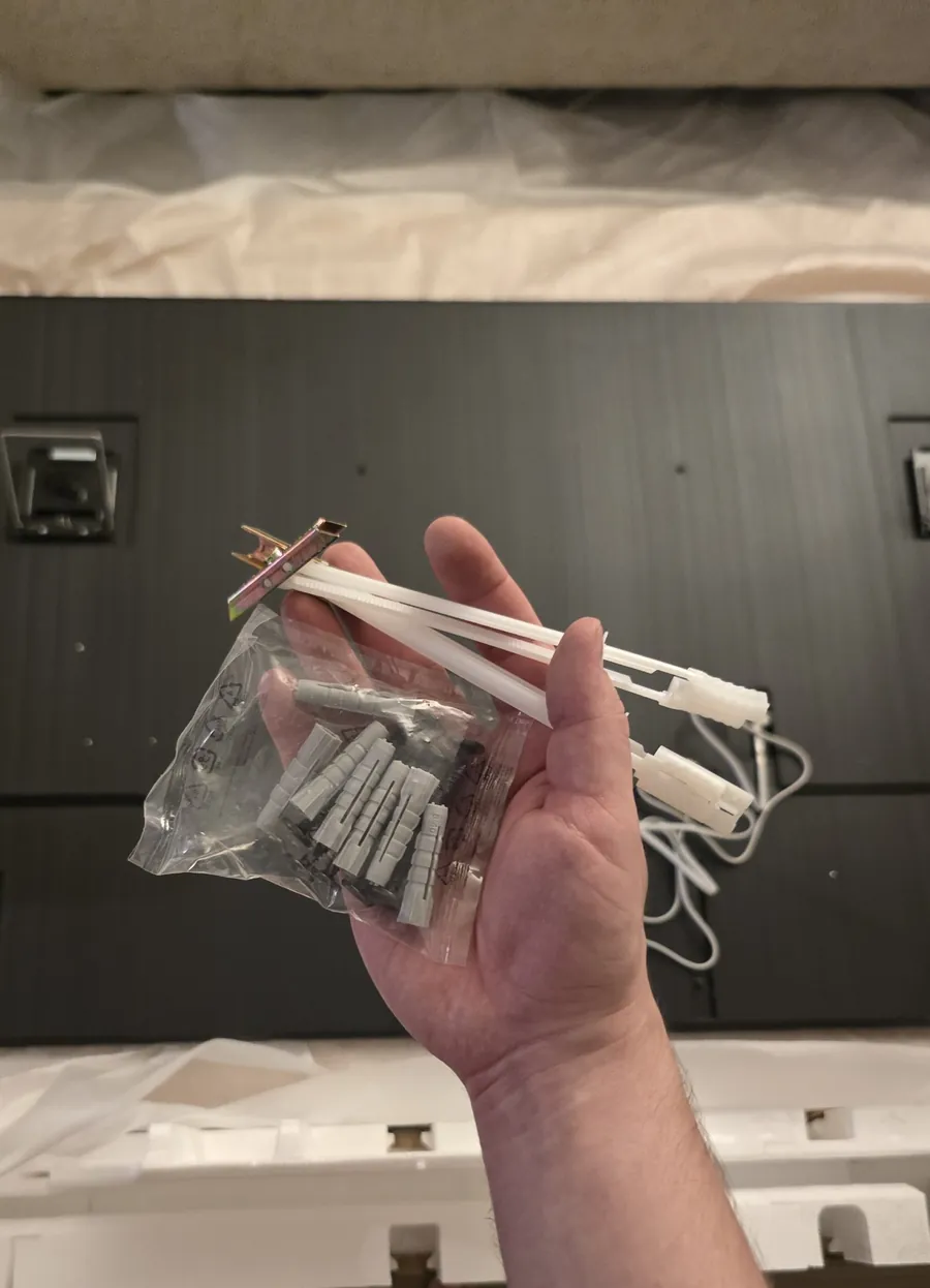 Gray wall anchors from the Samsung mounting kit and flip toggle bolts in a hand
