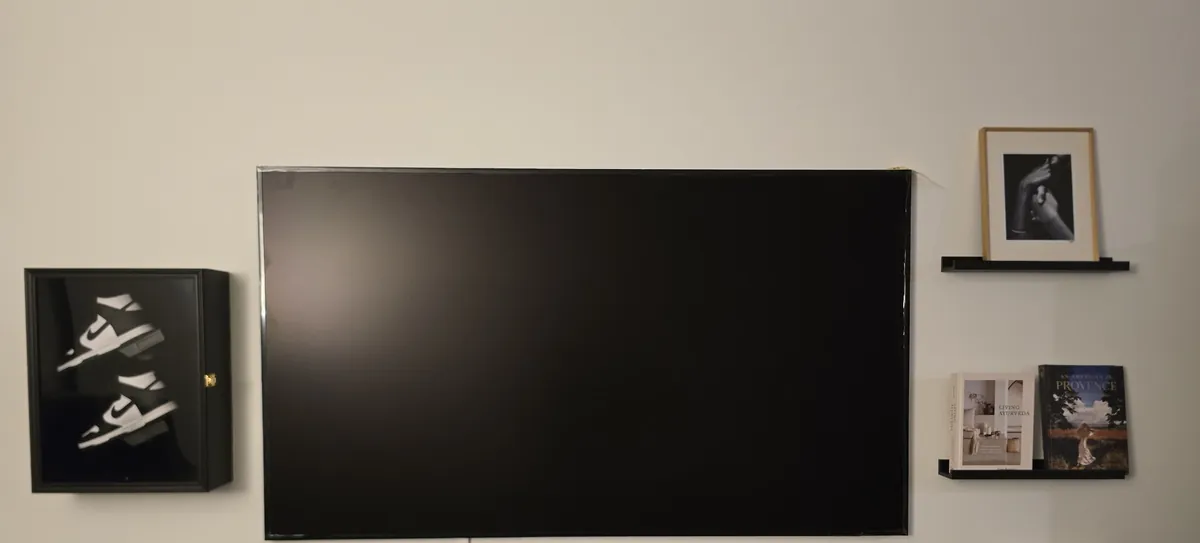 Samsung Frame TV hanging flush on the wall between a shadow box and picture shelves
