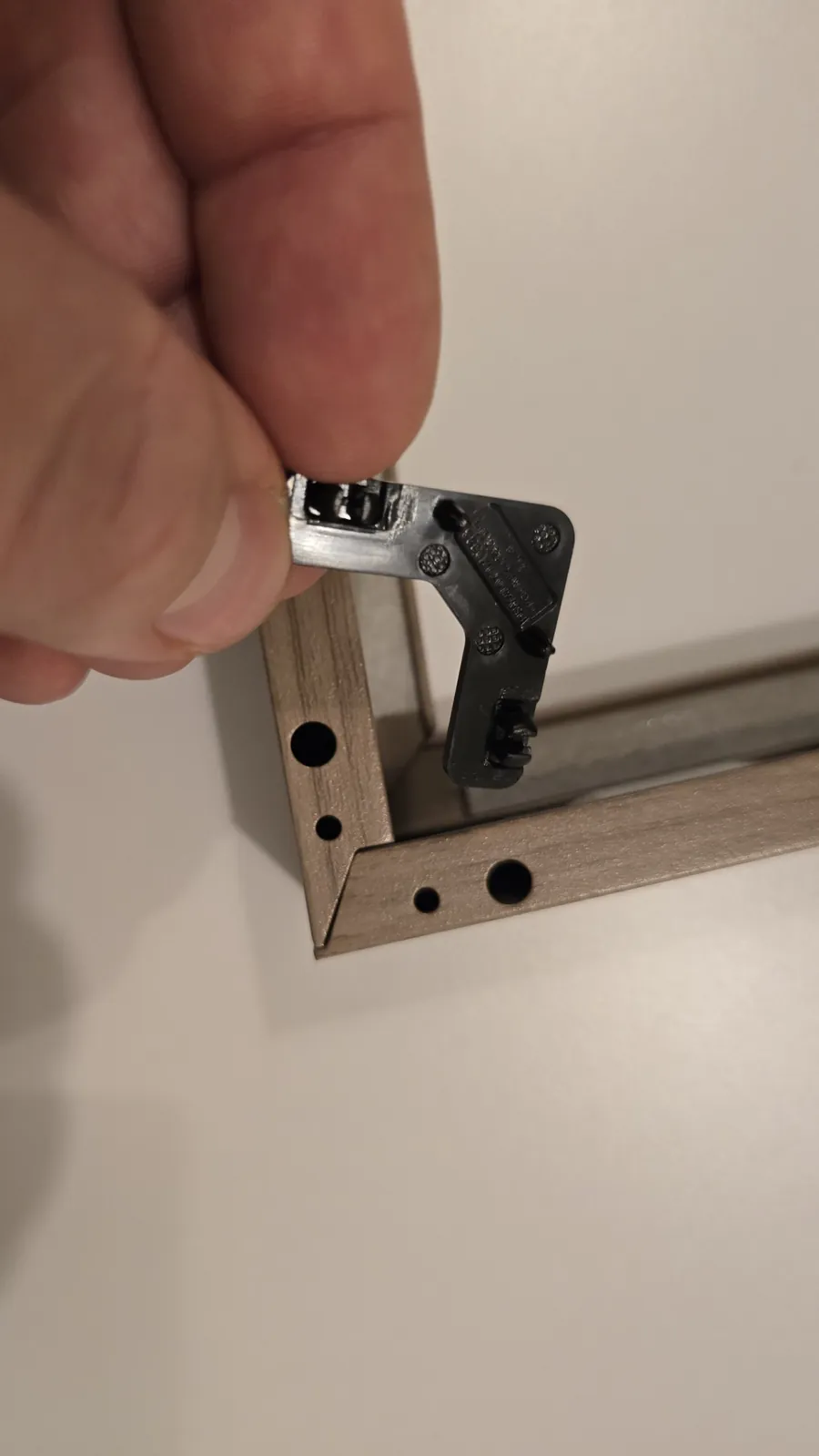 Black plastic connector being inserted into the end of a frame piece