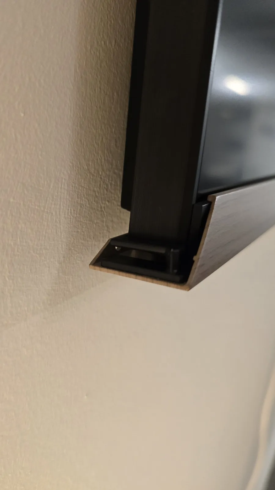 Side view of the bottom frame piece wrapping under the TV