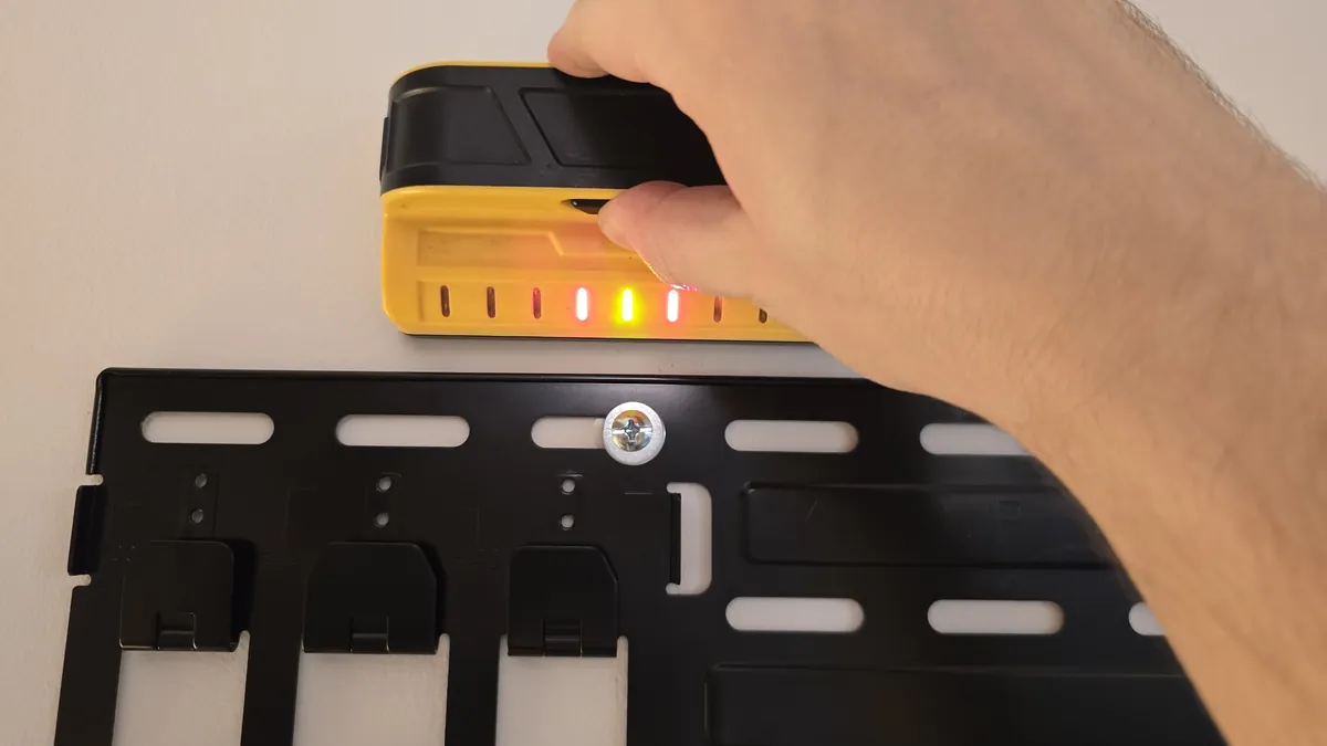 Stud finder lighting up above the Hisense wall mount plate