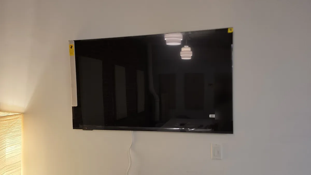 Hisense CanvasTV hanging on the wall with its protective stickers still on