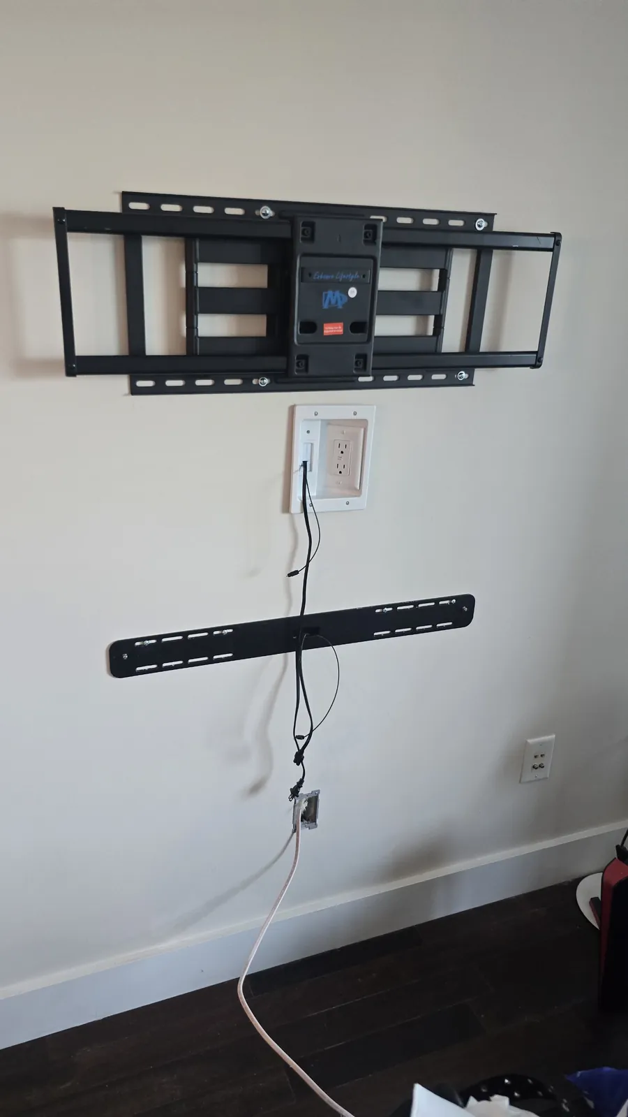 Finished in-wall power kit: recessed outlet behind the TV mount and a pass-through below the soundbar bracket