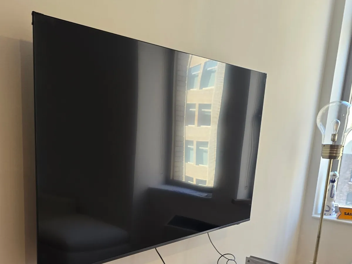TV mounted above a wooden media console by a window