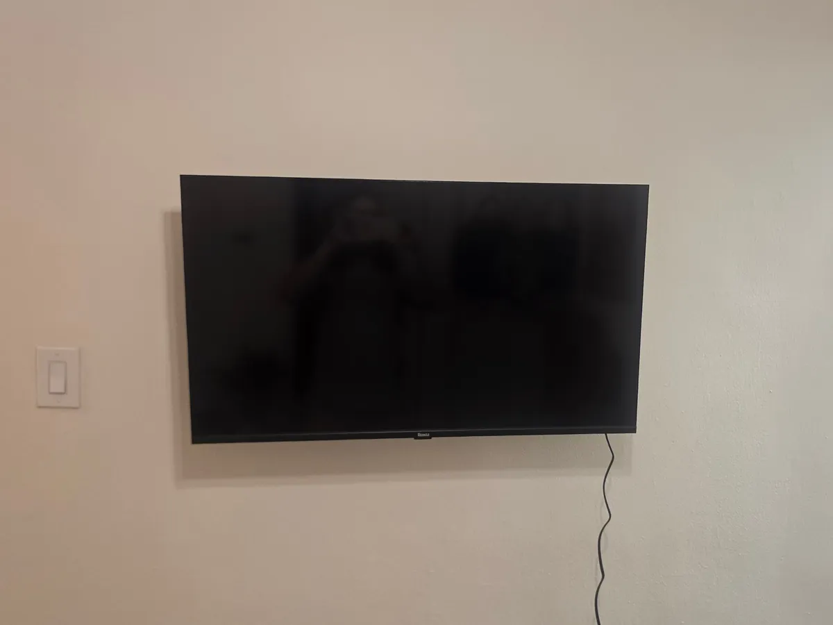 Roku TV flat-mounted on a wall next to a kitchen