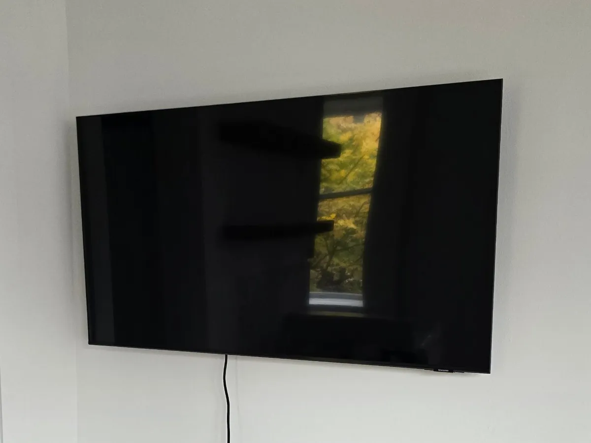Samsung TV mounted on a white wall in a corner nook
