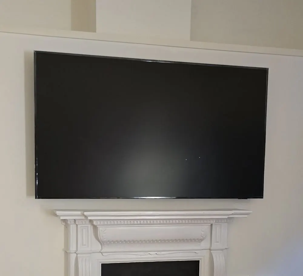 TV mounted above a white fireplace mantel