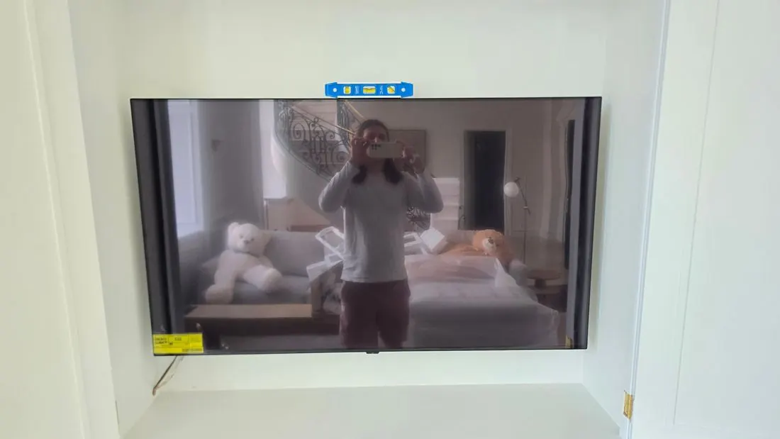 Large TV mounted level in a white alcove, with a level on top
