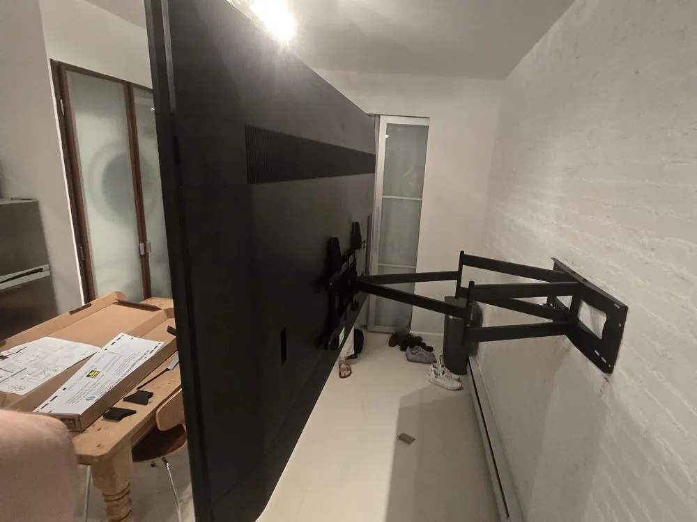 Large TV on a full-motion arm mounted to a brick wall