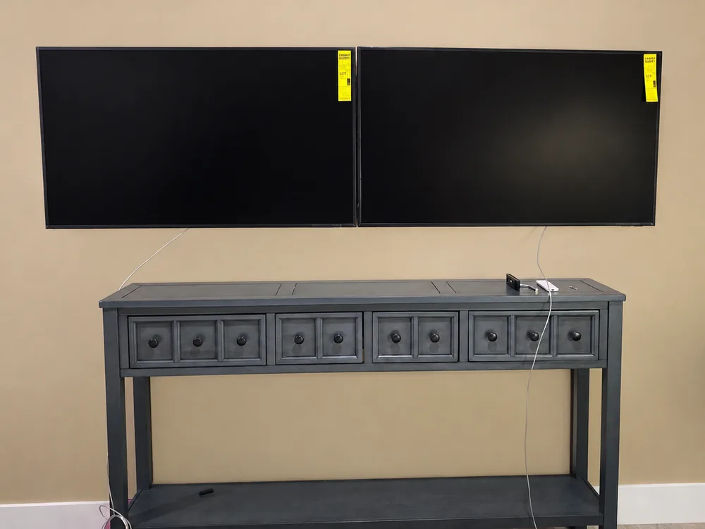 Two TVs mounted side by side above a console